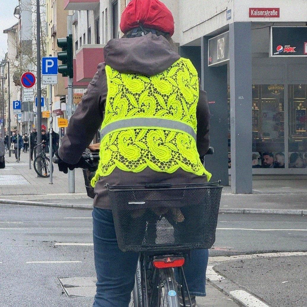 person on bike, wearing a high visability vest that has been crocheted with a repeating paisley motif