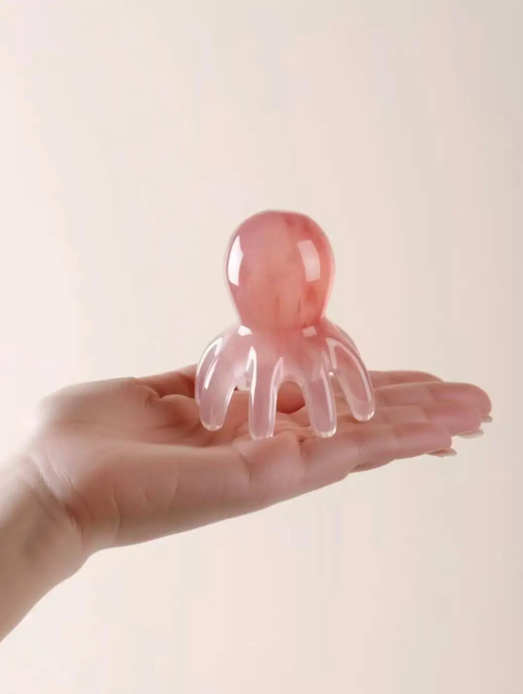 A pink thing like a petrified jellyfish standing "legs" down on an outstretched palm.